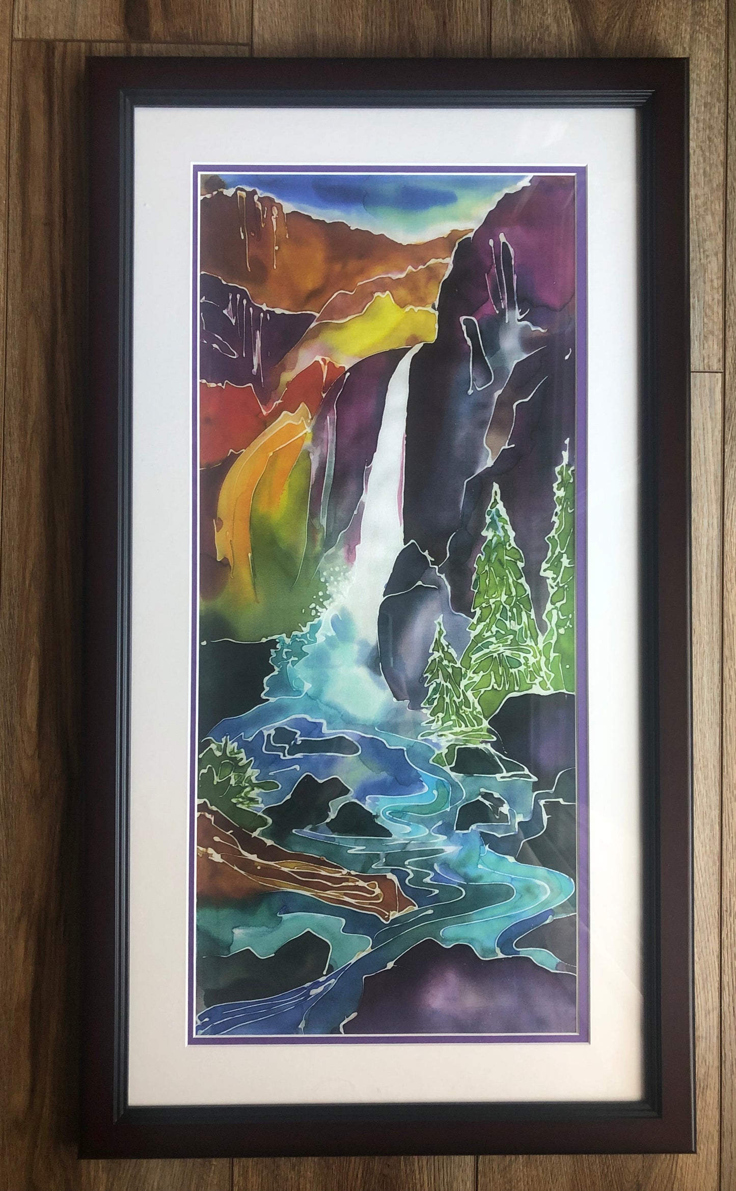 Framed waterfall painting artwork on a wooden wall